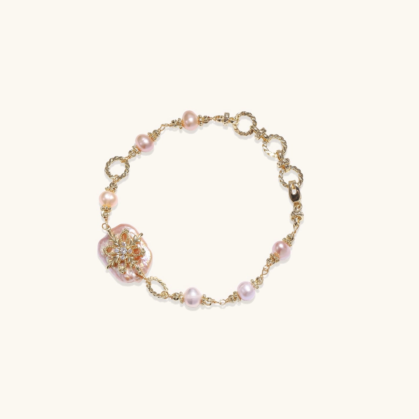 Gold-plated chain bracelet with baroque pearl centerpiece and floral charm, featuring mixed freshwater pearls.