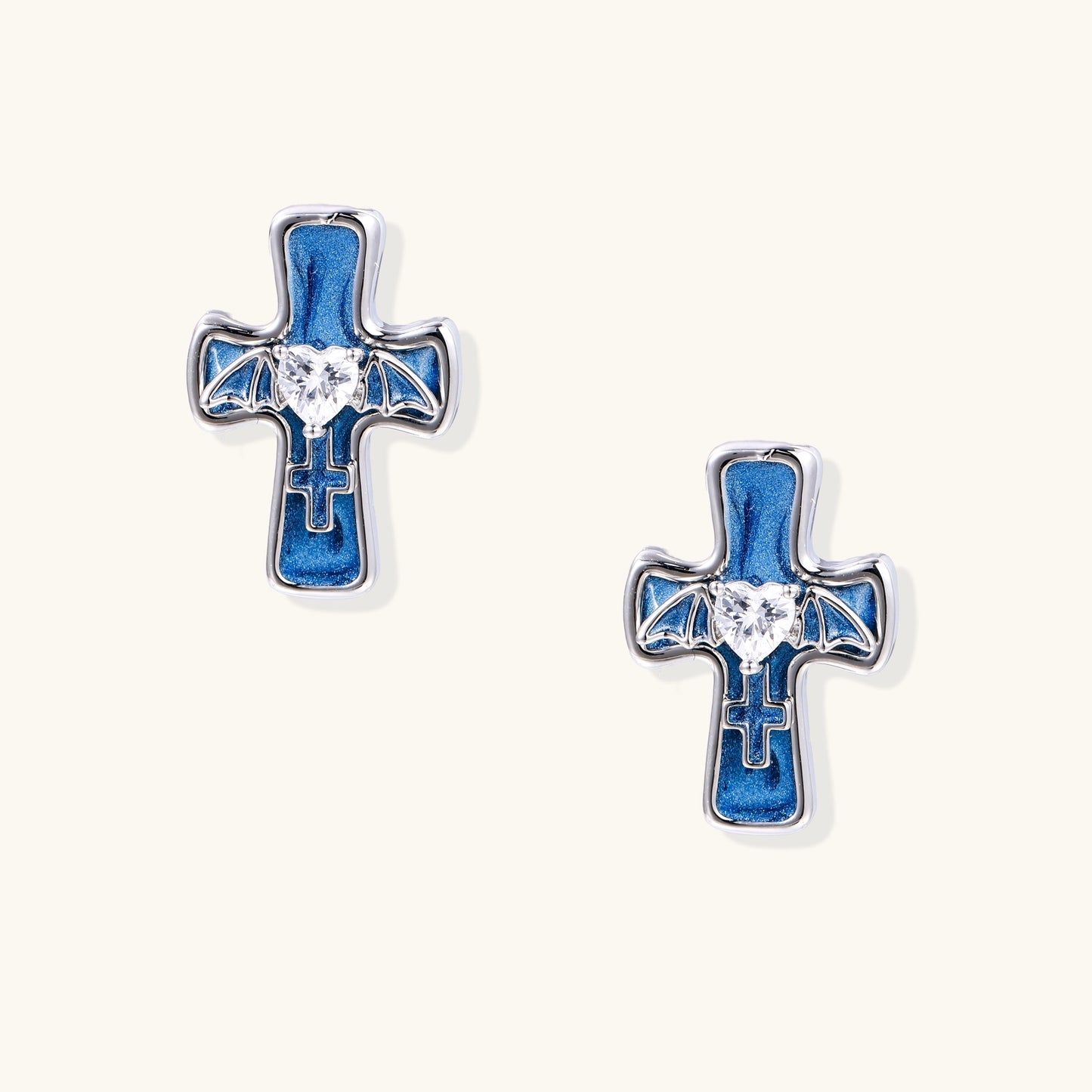 Blue enamel cross stud earrings with gold plating, clear zirconia center stones, and bat wing details on white background.