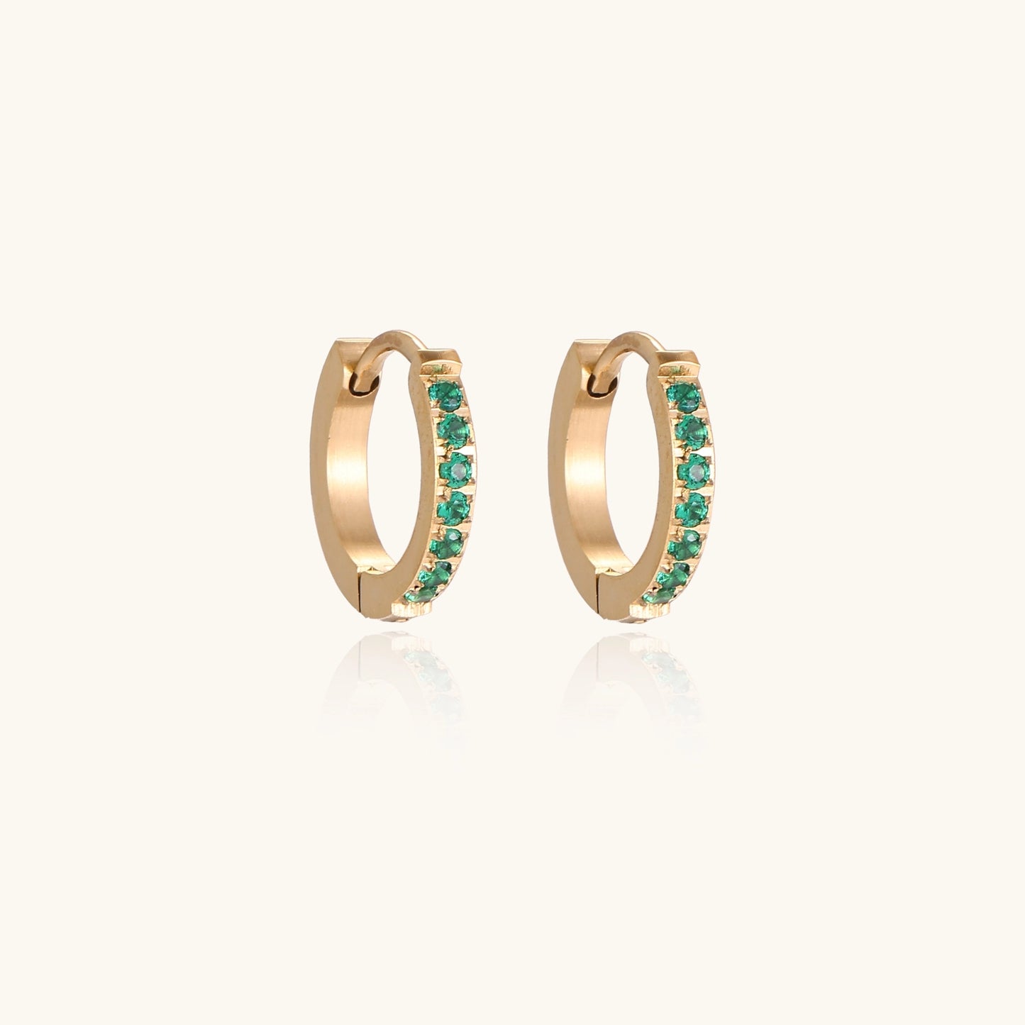Small gold-plated huggie hoop earrings with emerald green cubic zirconia stones, one open showing hinge mechanism