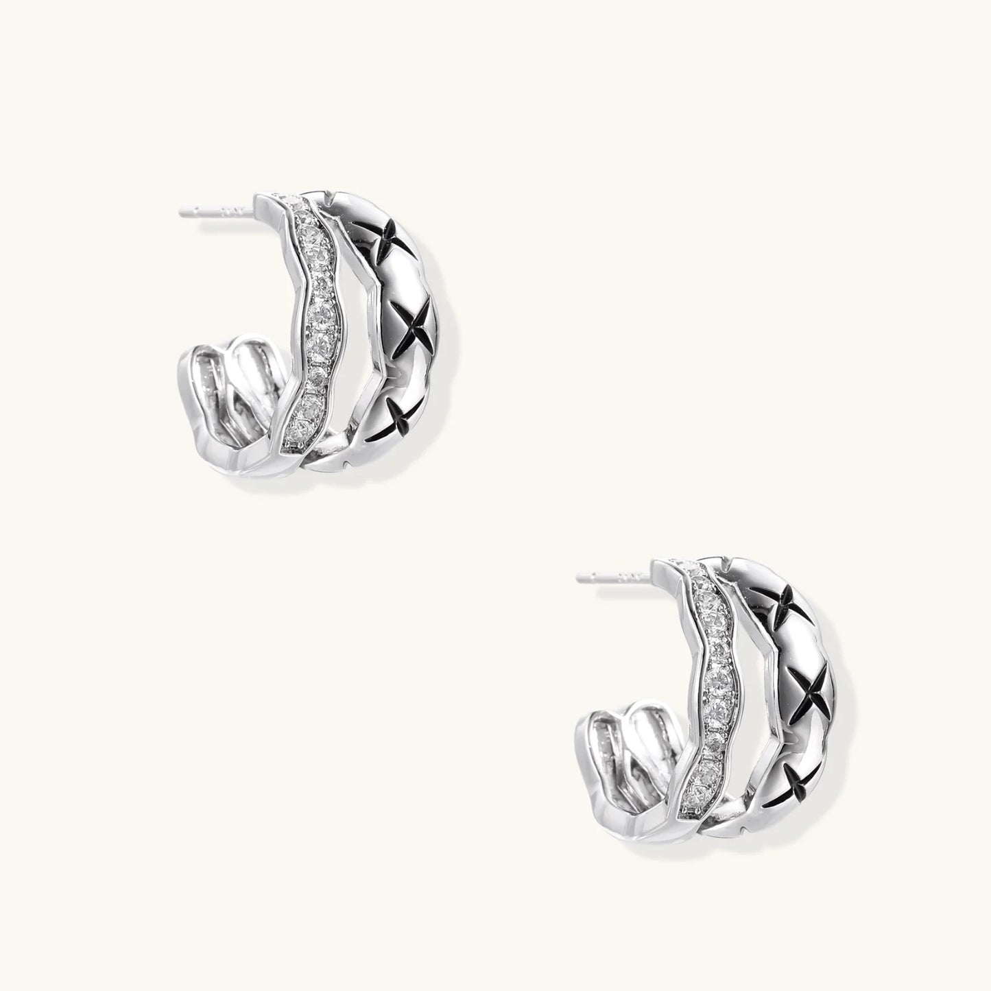 Triple-row white gold hoops with black X-pattern, twisted band, and pavé zirconia stones on white background.