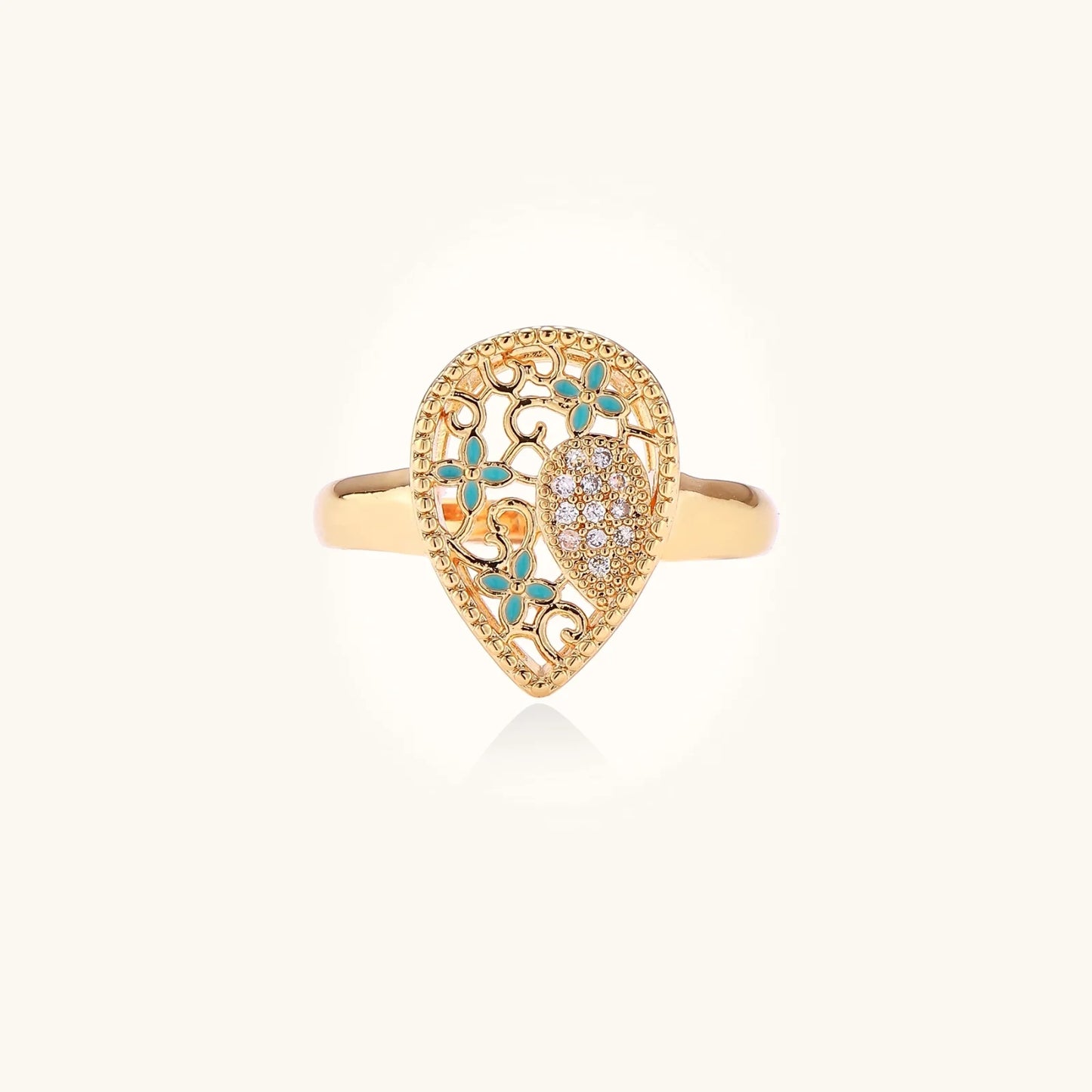 Teardrop-shaped gold-plated ring with turquoise enamel flowers and crystal pavé detail on cream background