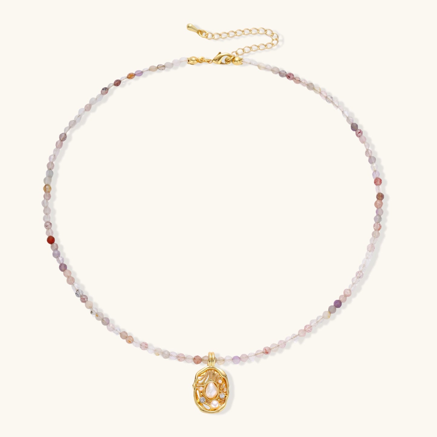 Delicate gold-plated necklace with mixed gemstone beads and ornate oval pendant on white background