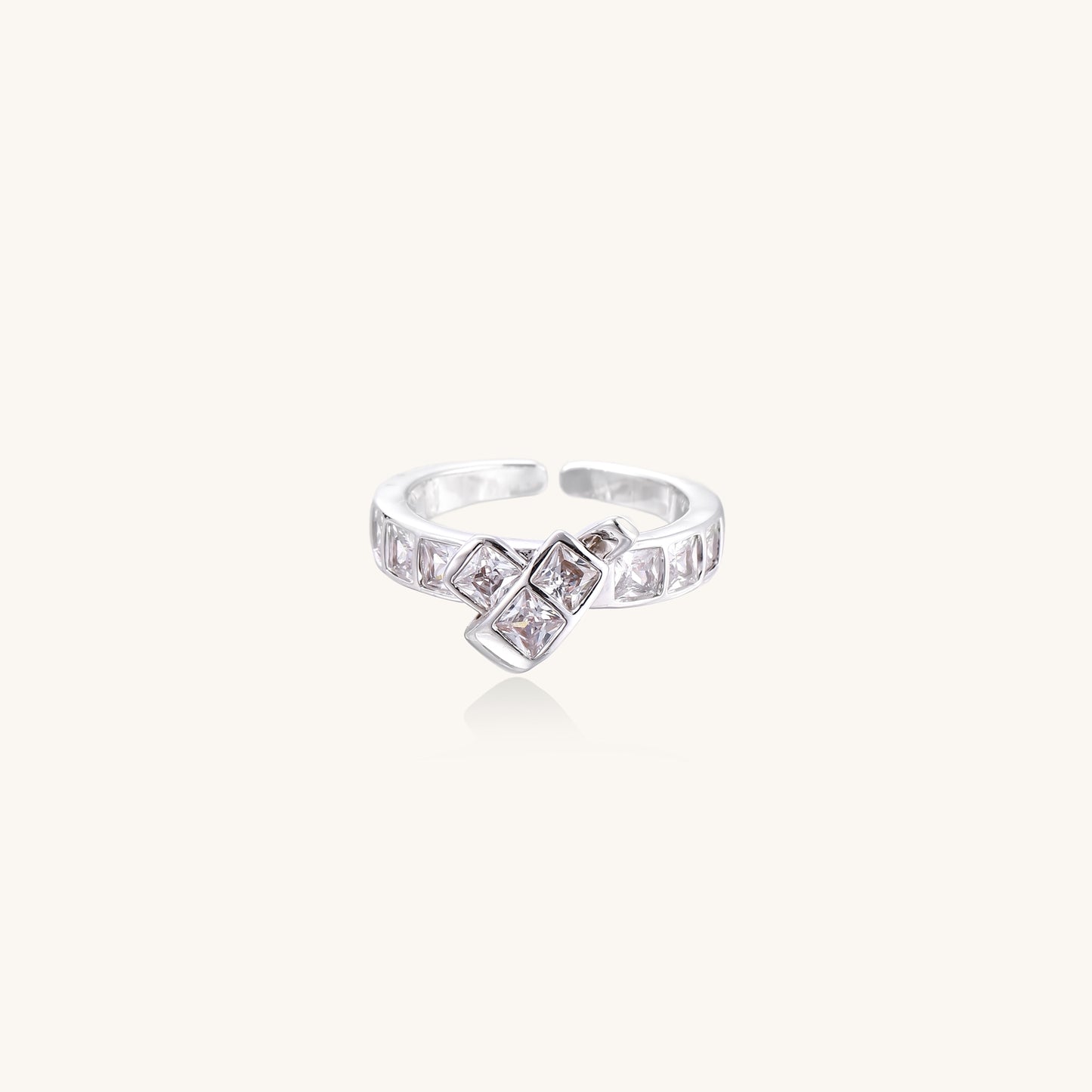 Close-up of geometric gold-plated brass ring with square-cut zirconia stones in architectural tiered design on white background.