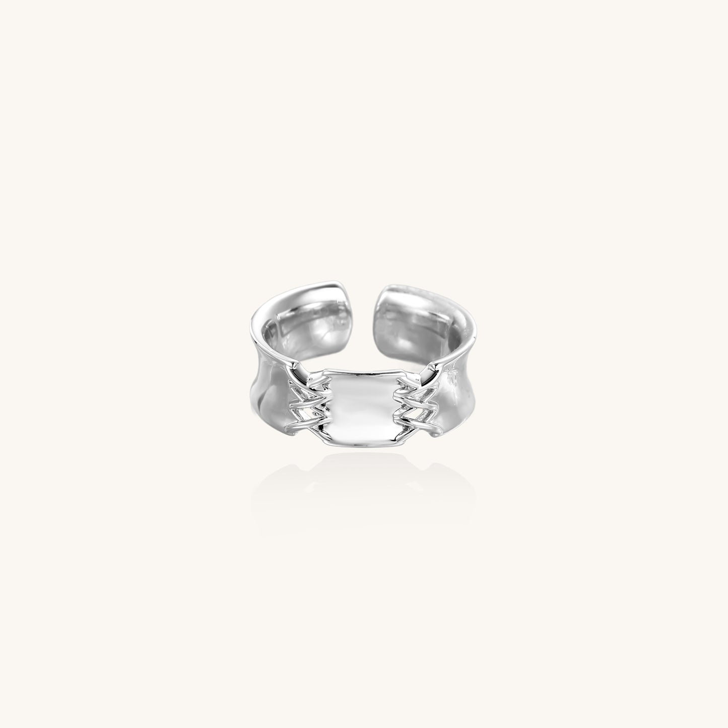 Chunky gold plated brass cuff ring with chain link details connecting two wide bands on neutral background.