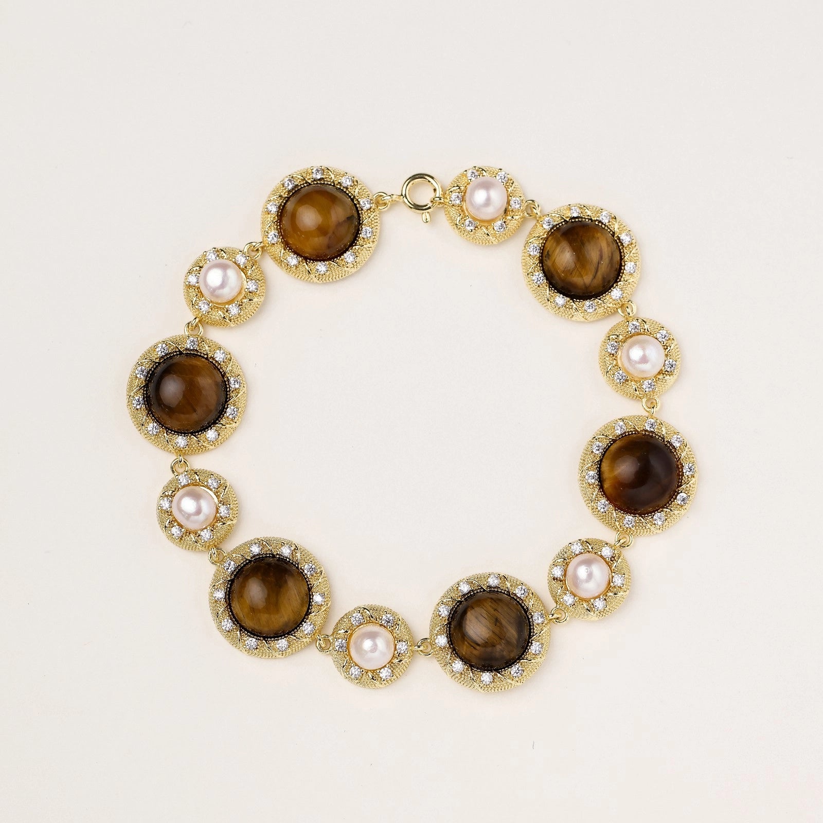 Ornate gold-plated bracelet with alternating brown tiger's eye stones and white freshwater pearls in crystal-accented settings