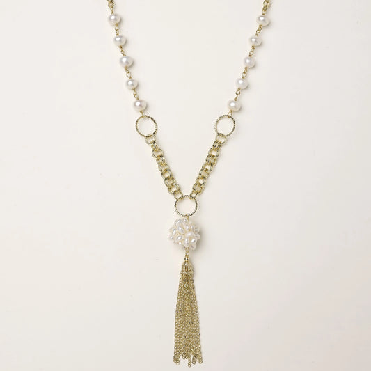 Layered gold-plated necklace with freshwater pearls, central pearl cluster, and chain tassel on cream background.