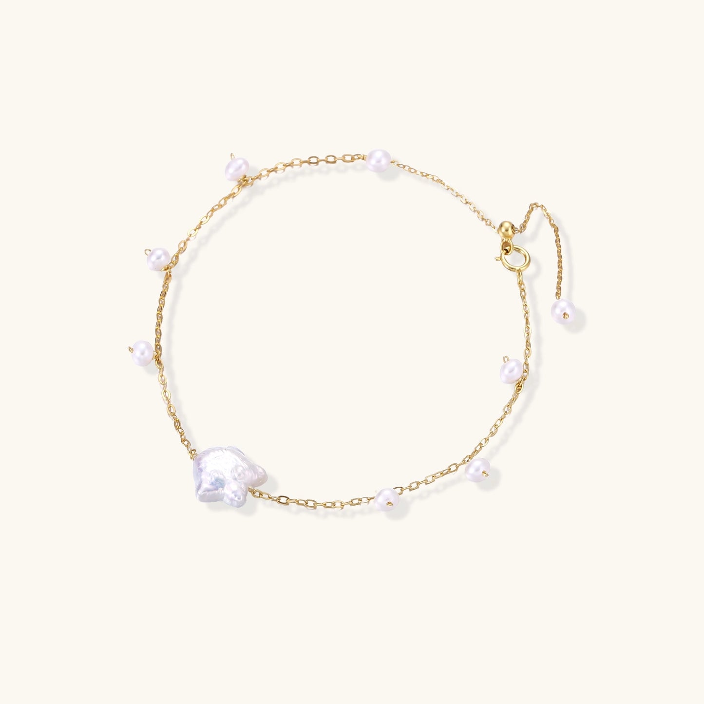 Delicate 18K gold-plated silver chain bracelet with freshwater and baroque pearls on cream background
