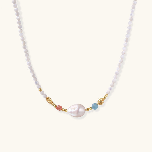 Delicate white beaded necklace with central freshwater pearl and gold-toned emerald accents on white background.
