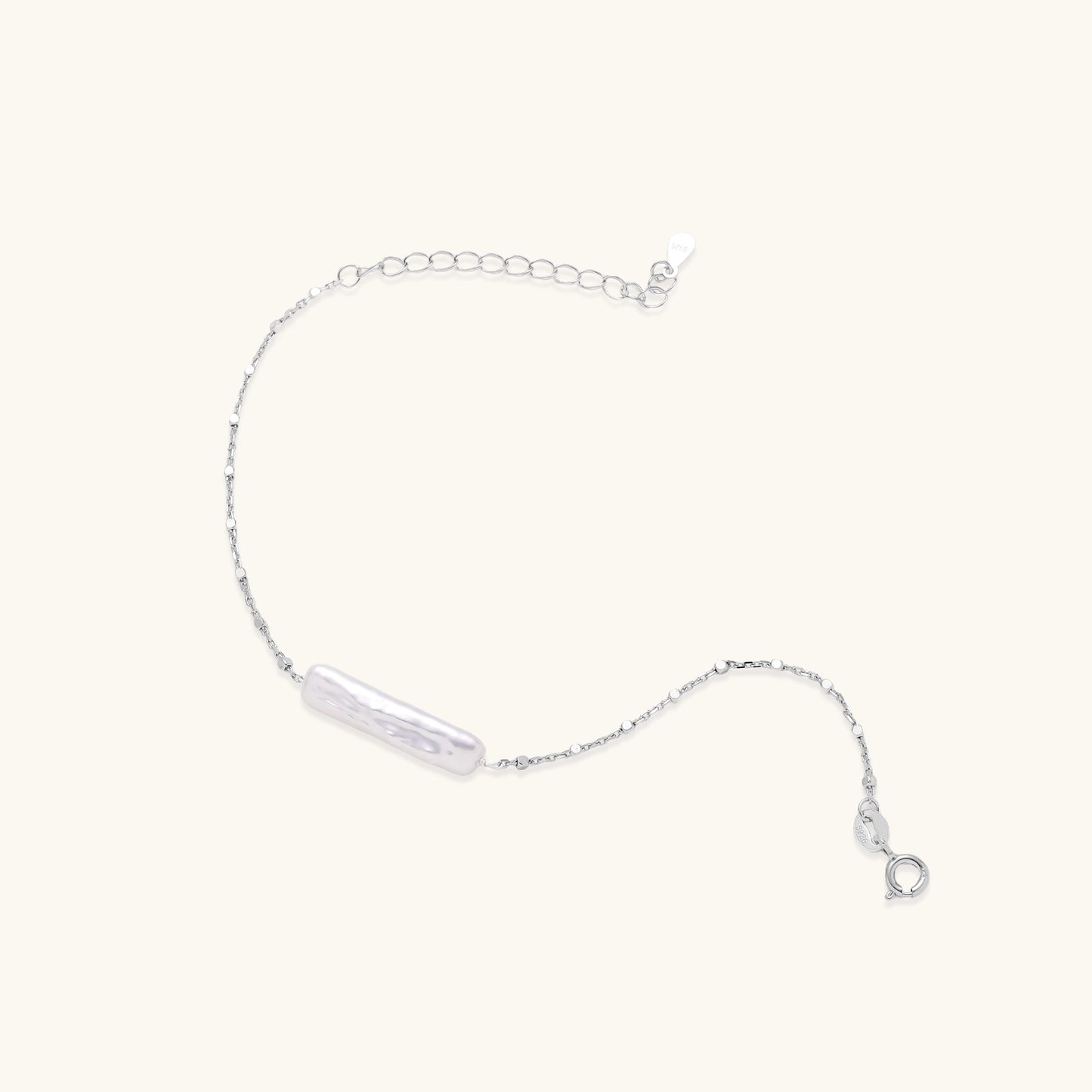 Delicate sterling silver chain bracelet with an organic white baroque pearl centerpiece on neutral background