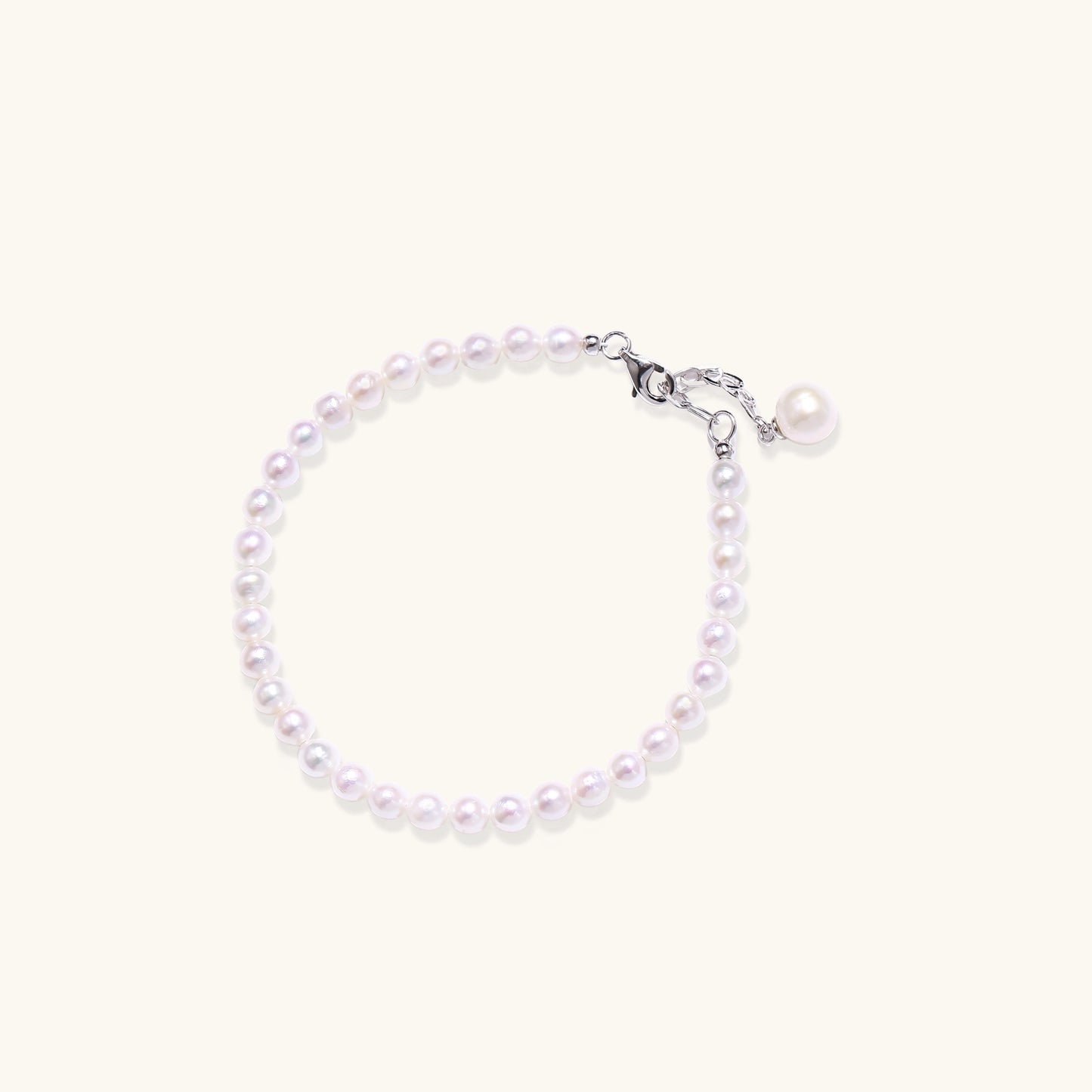 Delicate sterling silver bracelet with small freshwater pearls and adjustable chain on neutral background.