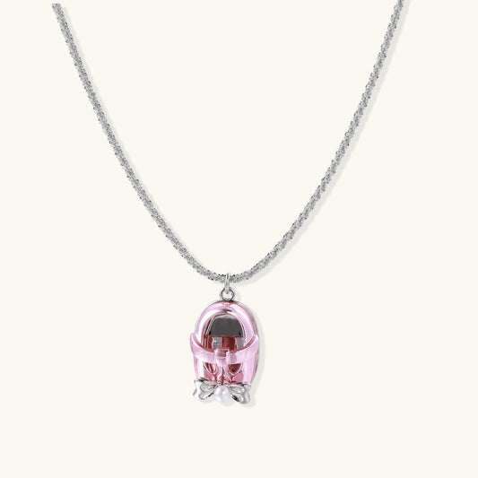 Delicate gold-plated chain necklace with transparent pink-tinted capsule pendant containing decorative bow element