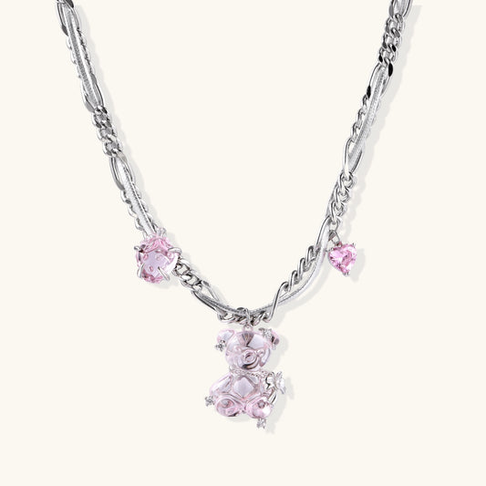 Adjustable gold-plated brass chain necklace with pink zirconia crystals and mixed link patterns on white background.