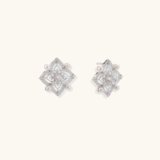 Detailed view of sterling silver stud earrings with geometric filigree design and small freshwater pearls on white background.
