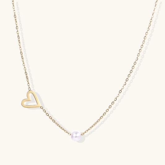Dainty 14K gold-plated necklace with open heart pendant and white pearl bead on neutral background