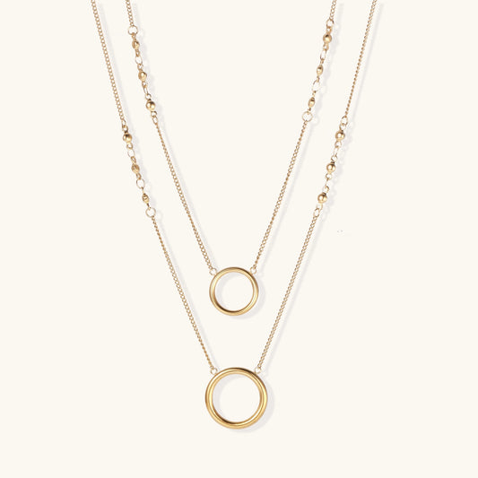 Gold-plated layered necklace set with two circular pendants featuring white centers on delicate chains.