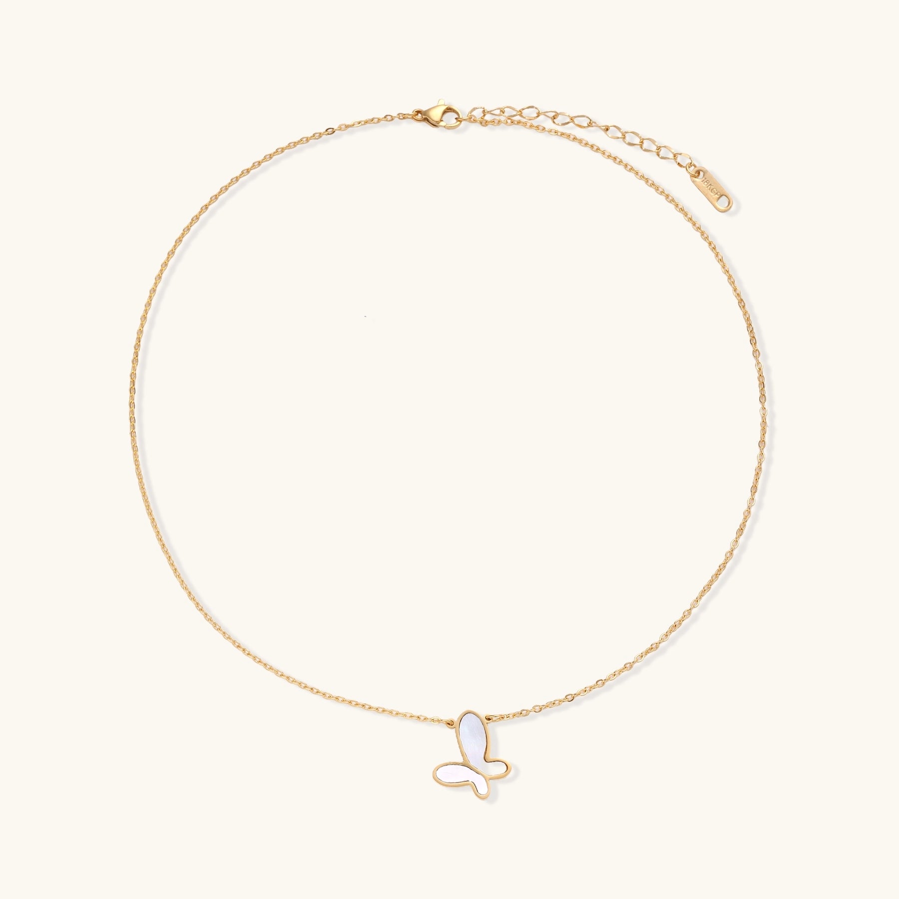 Delicate gold butterfly necklace with white mother of pearl wings on fine chain, displayed on neutral background.