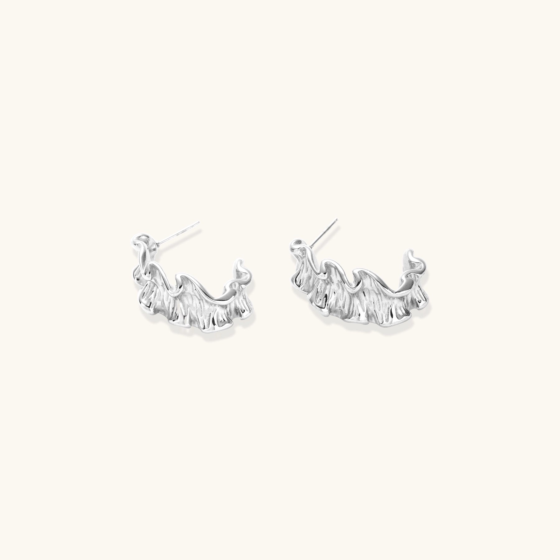 Textured gold-plated hoop earrings with flowing ripple design displayed on clean white background.