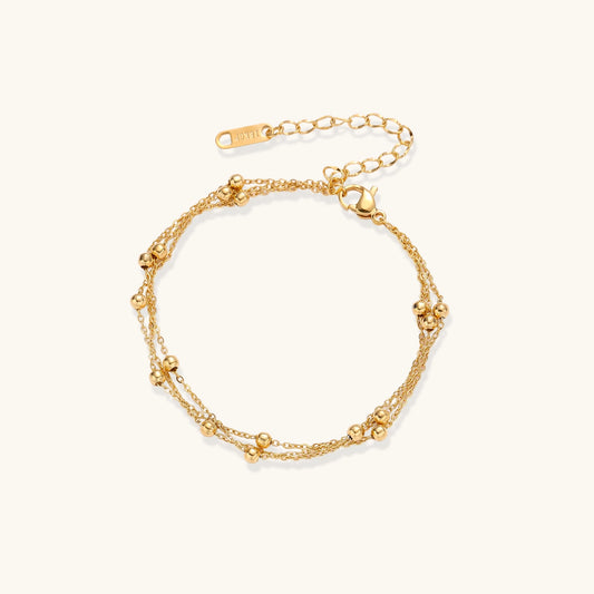 Delicate 18K gold plated bracelet with spherical beads on layered chains and adjustable extender on white background