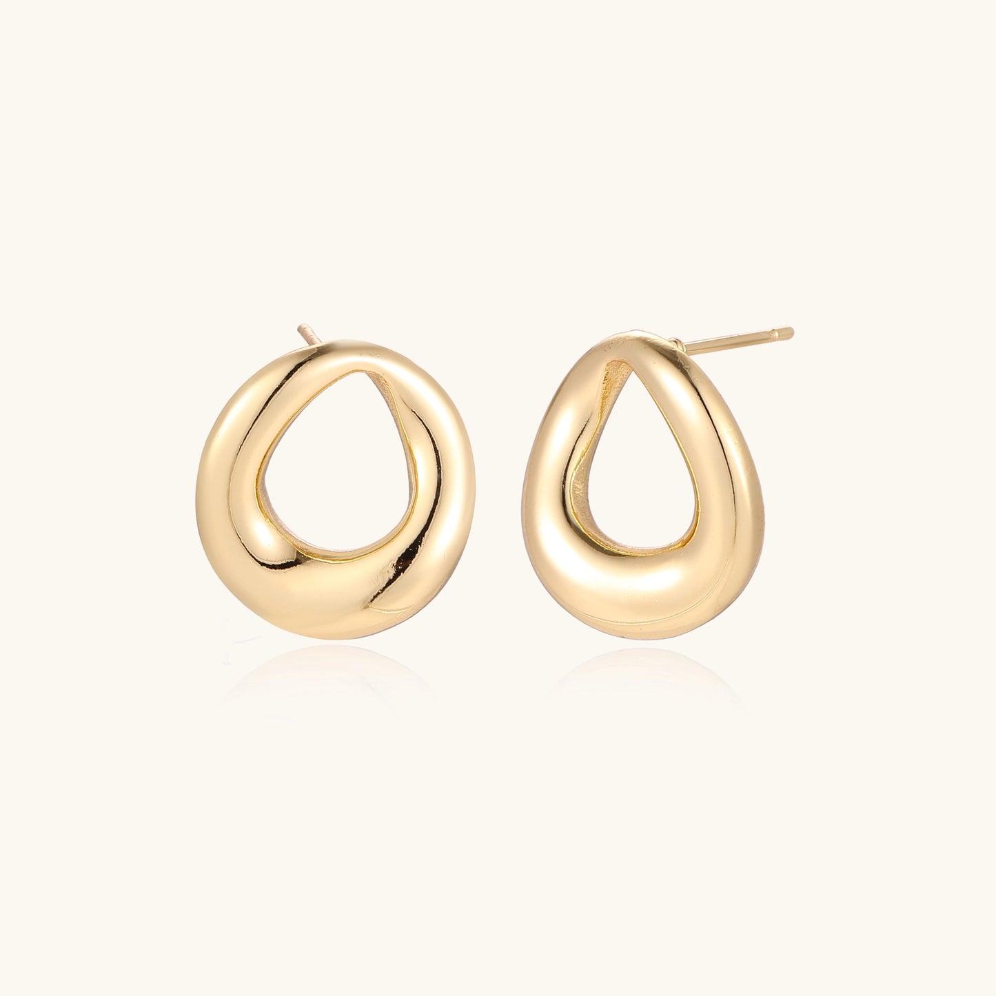 Pair of polished 18K gold-plated stainless steel oval loop stud earrings on cream background