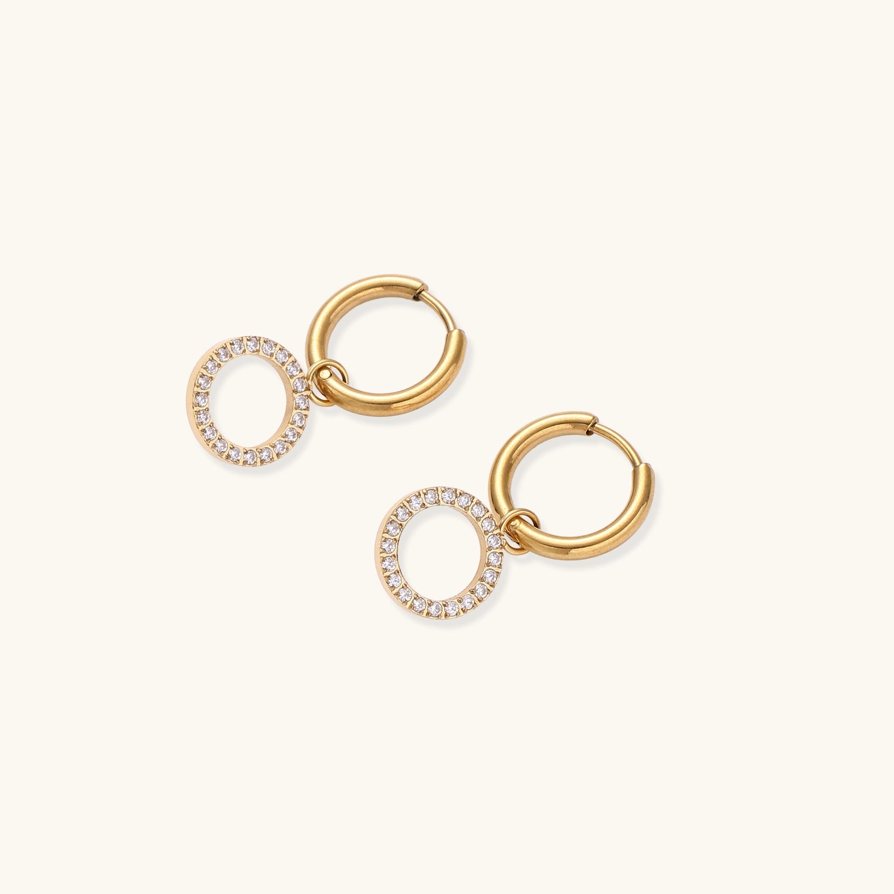 Gold-plated hoop earrings with circular cubic zirconia charm dangles displayed on neutral background.