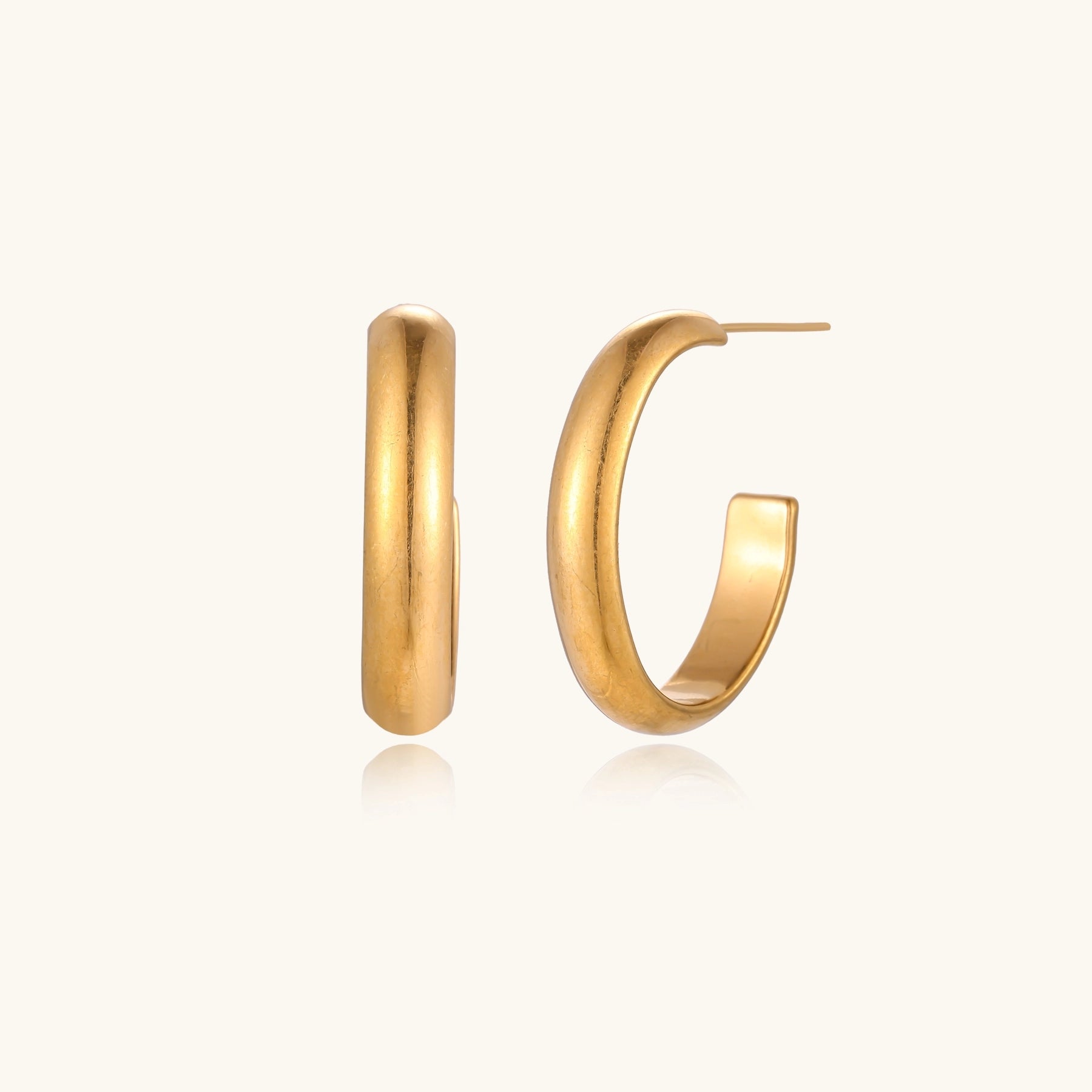 Four pairs of gold-plated stainless steel earrings including hoops and studs displayed on cream background