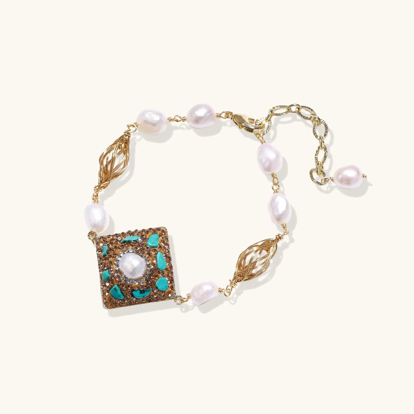 Gold-plated bracelet with baroque centerpiece, turquoise stones, freshwater pearls, and ornate chain links on cream background.