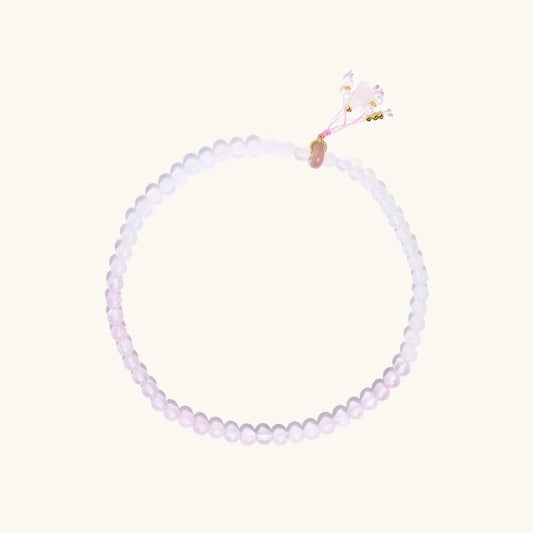 Double-wrap lavender beaded bracelet with rose quartz, pearls, gold vermeil charm and pink tassel on white background.