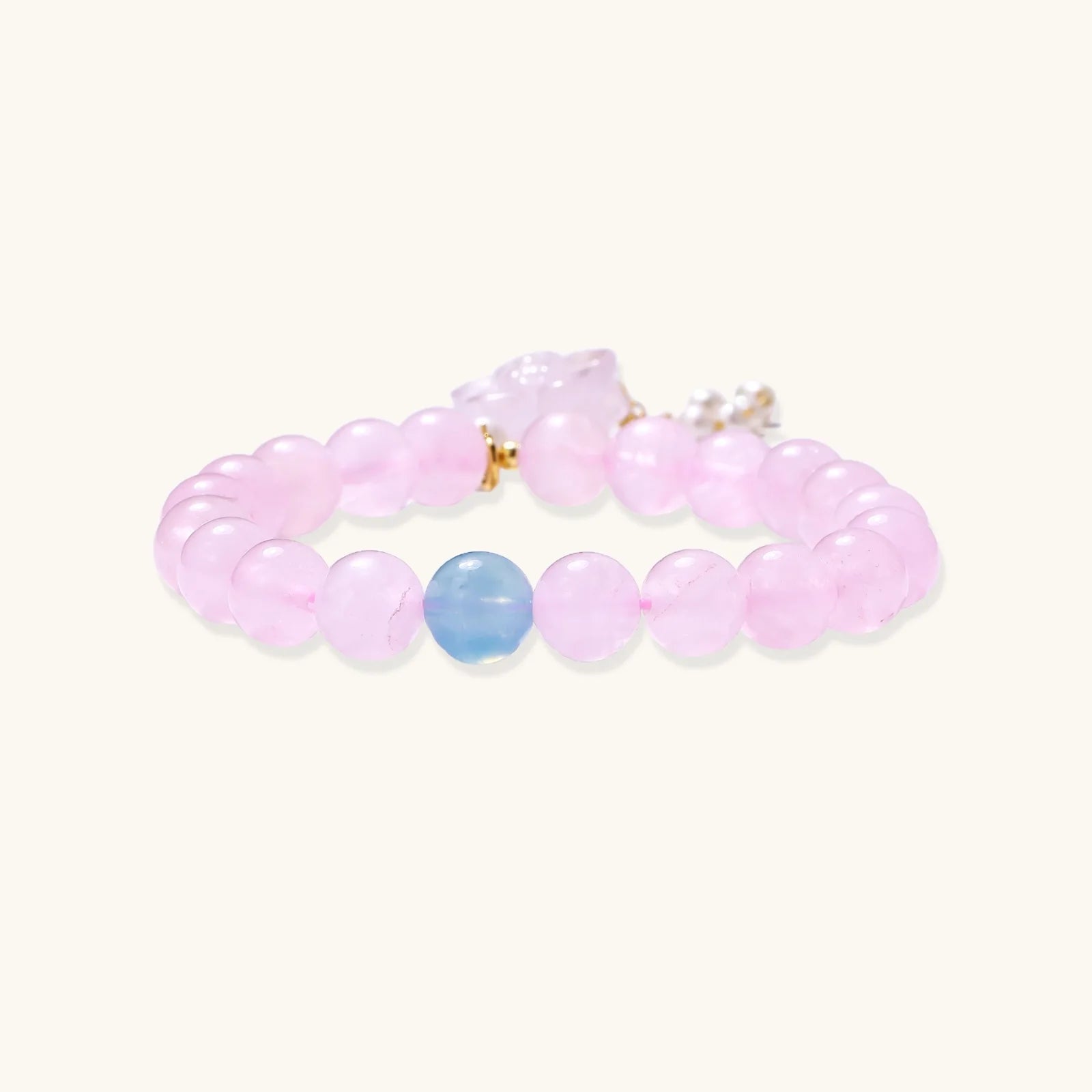 Stretchy beaded bracelet with pink rose quartz, blue aquamarine, carved floral pendant, and pearl tassel clasp.
