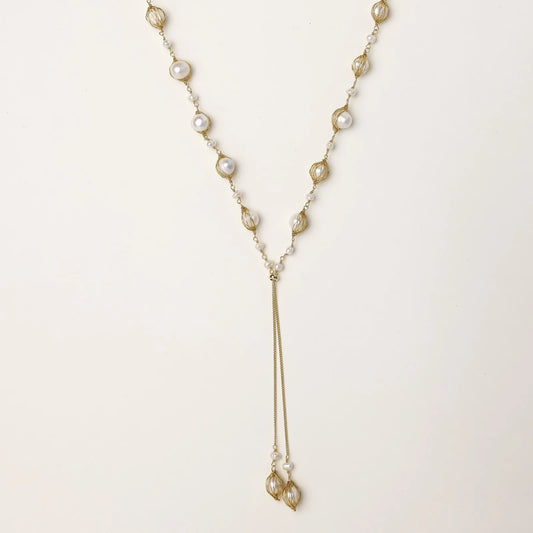 Adjustable gold lariat necklace with freshwater pearls nested in delicate cage settings and Y-shaped tassel drop
