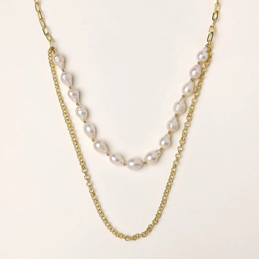 Layered gold chain necklace with organic baroque freshwater pearls and adjustable length on cream background