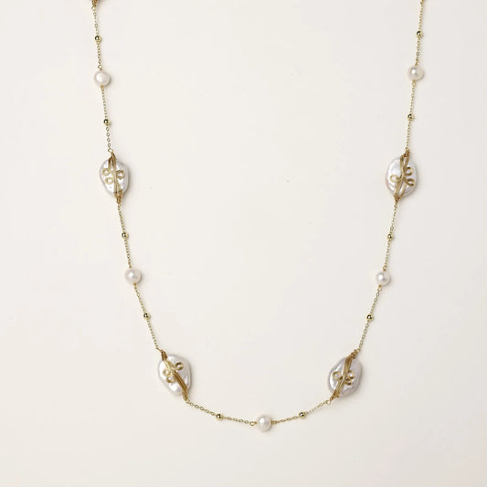 Long gold chain necklace with baroque pearls wrapped in leaf designs and small freshwater pearls spaced along the strand