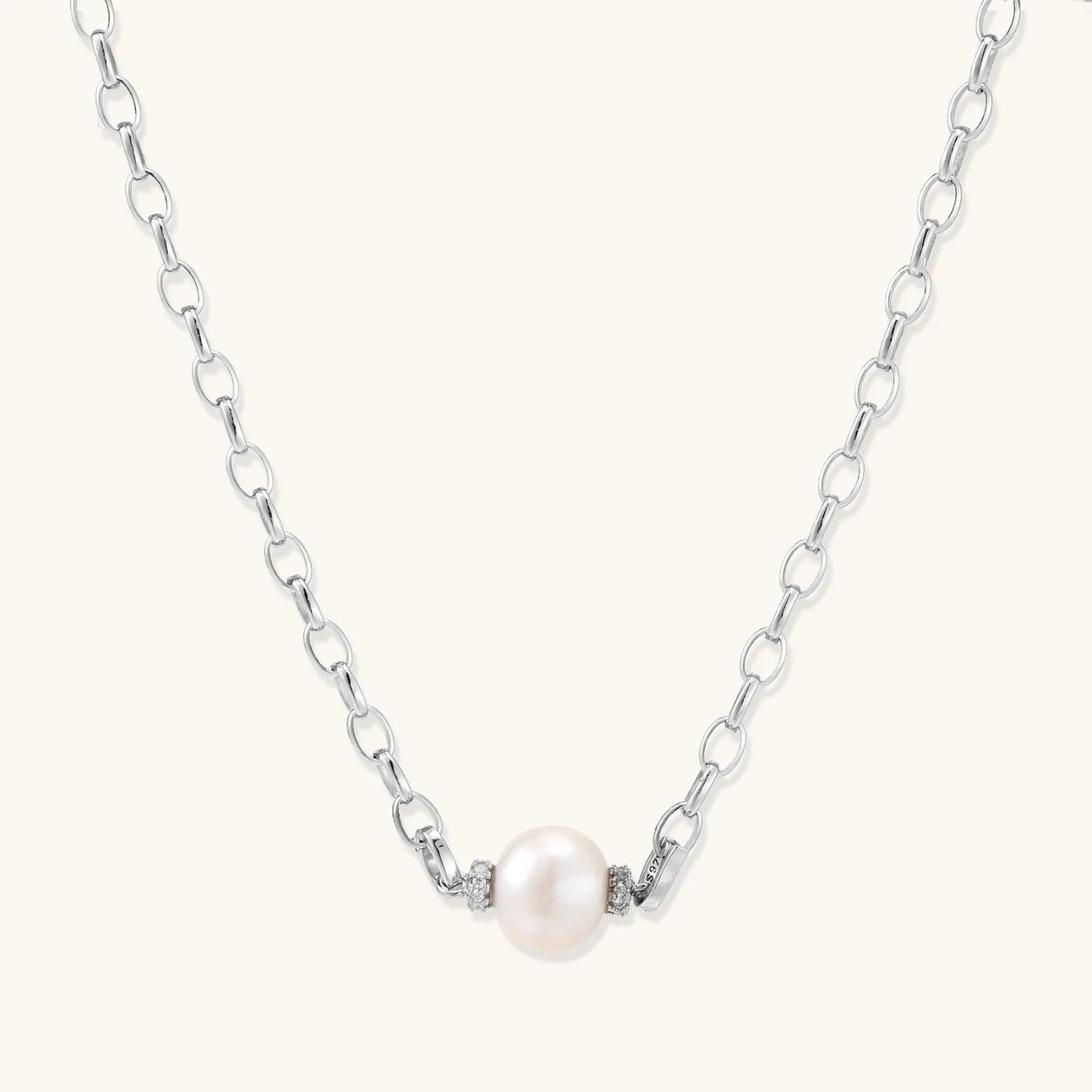 Dainty rhodium-plated silver chain necklace with centered 10mm freshwater pearl and crystal accents on cream background