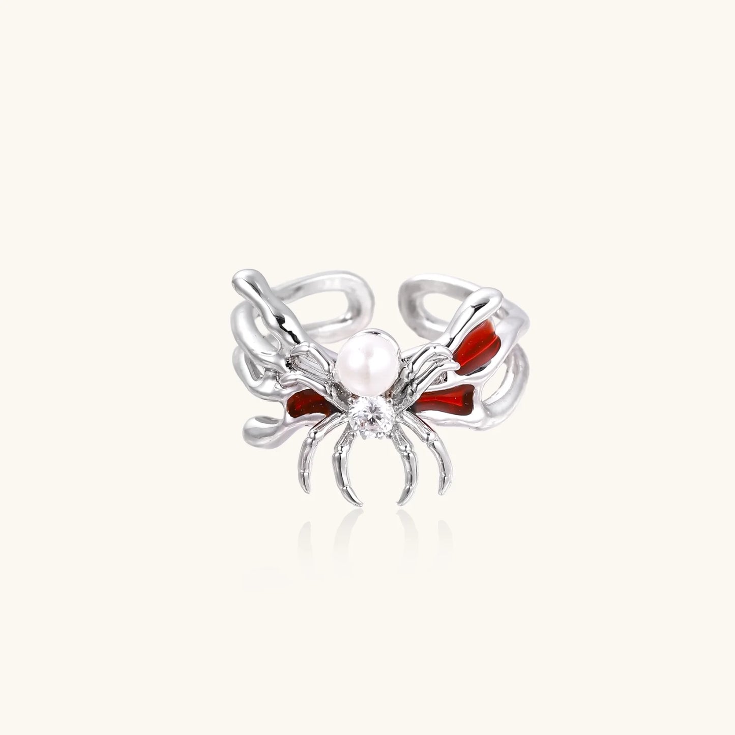 White gold plated spider ring with pearl body, clear zirconia center, and red enamel leg accents on adjustable band