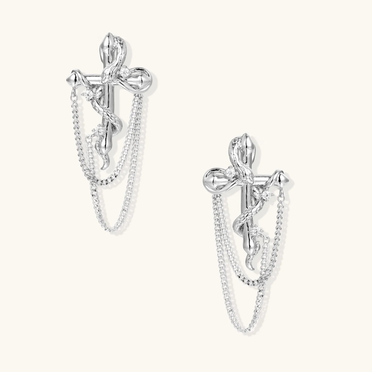 Sculptural white gold bow earrings with cascading chain details on neutral background
