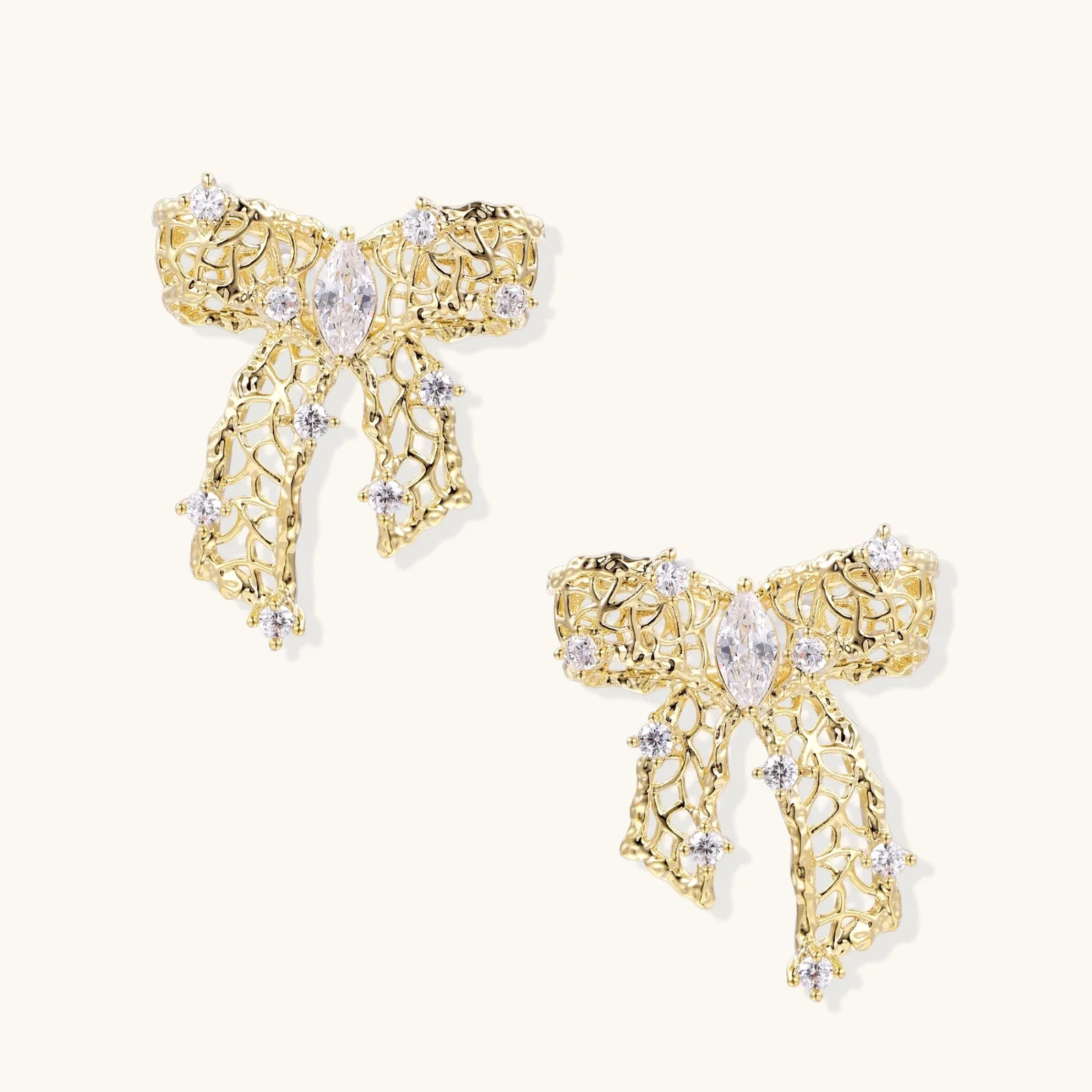 Filigree bow-shaped earrings with marquise center stone and lattice ribbon tails in gold and silver finishes