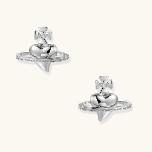 Polished white gold-plated Saturn planet stud earrings with orbital rings and crystal-centered cross on beige background