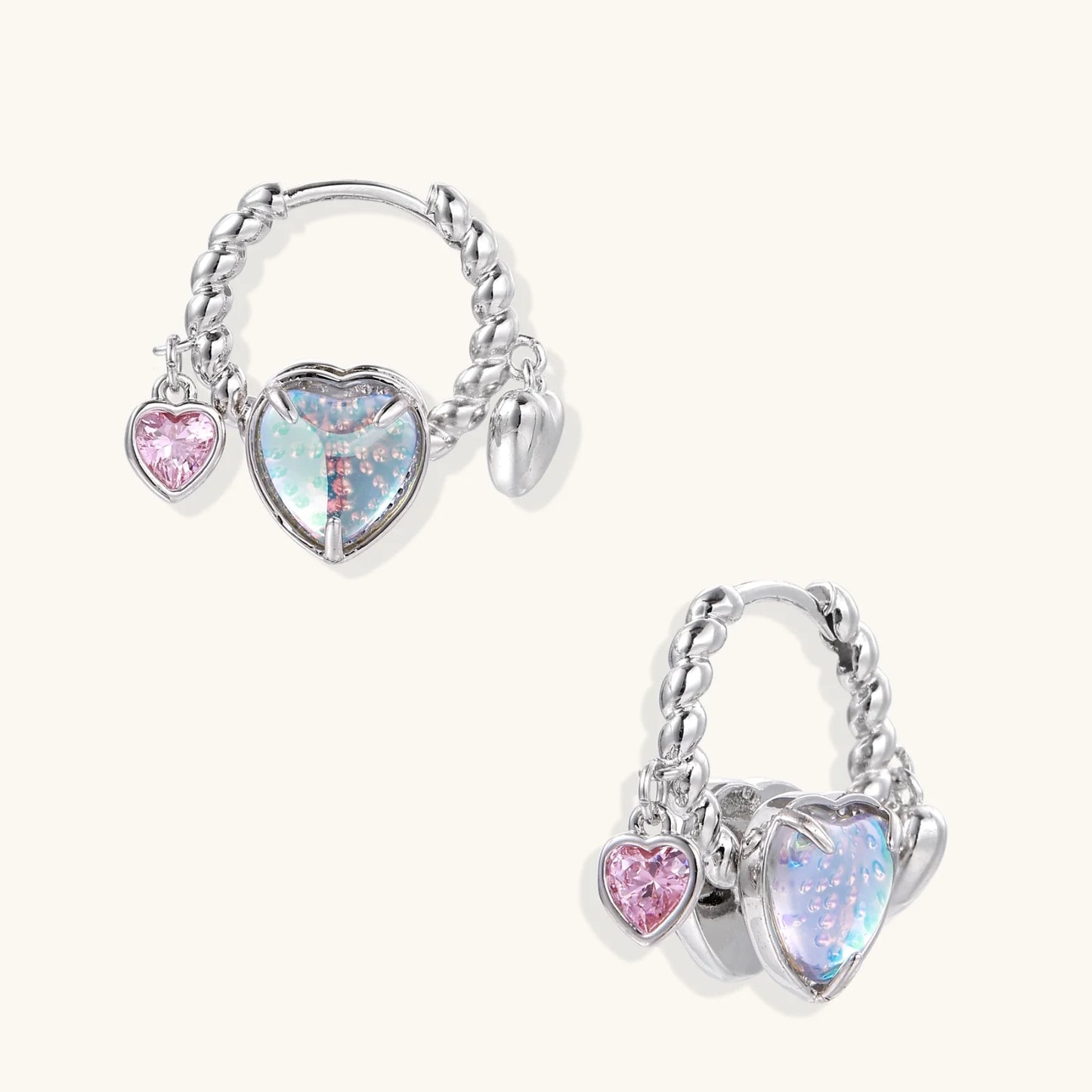 Silver chain hoop earrings with iridescent opal heart charms and pink zirconia accents on white background