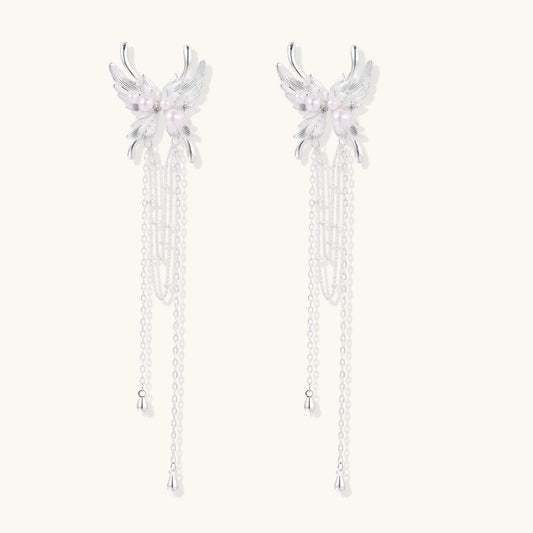 Elegant chandelier earrings with phoenix wing design, white pearls, and cascading silver chains on cream background