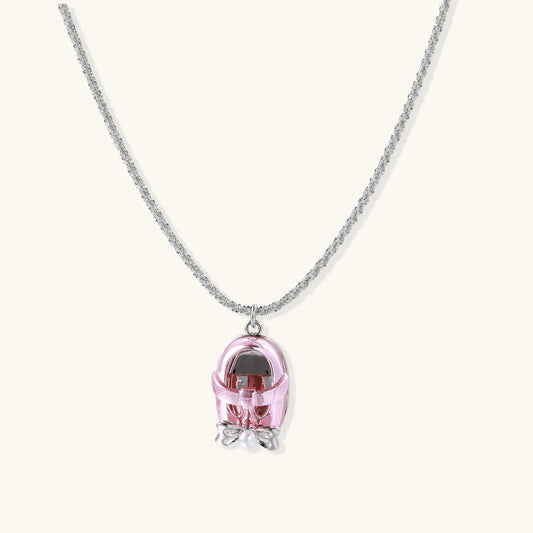 Translucent pink skull pendant with silver bow detail on delicate white gold plated chain against cream background