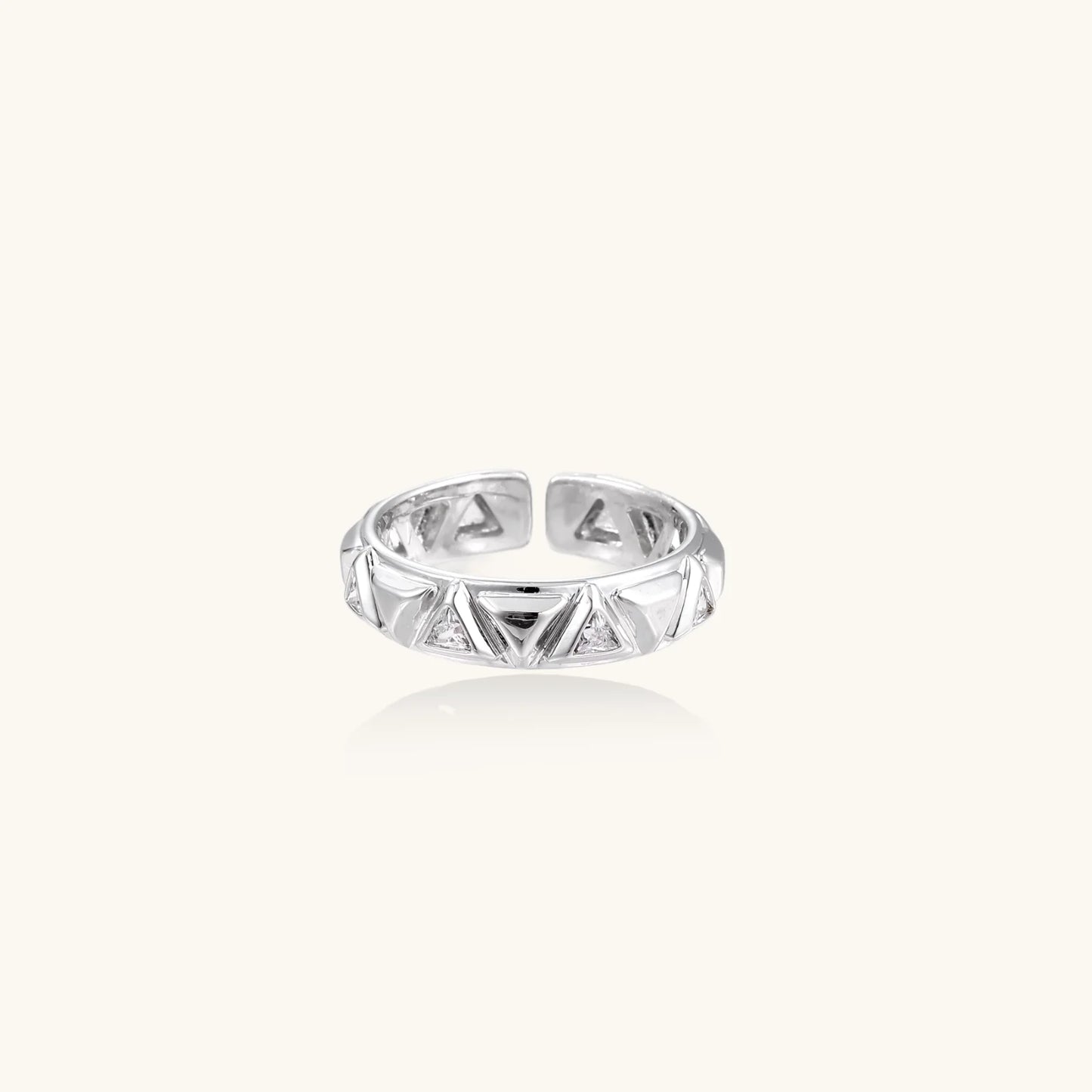 White gold adjustable ring with geometric triangle cutouts and zirconia stones on cream background