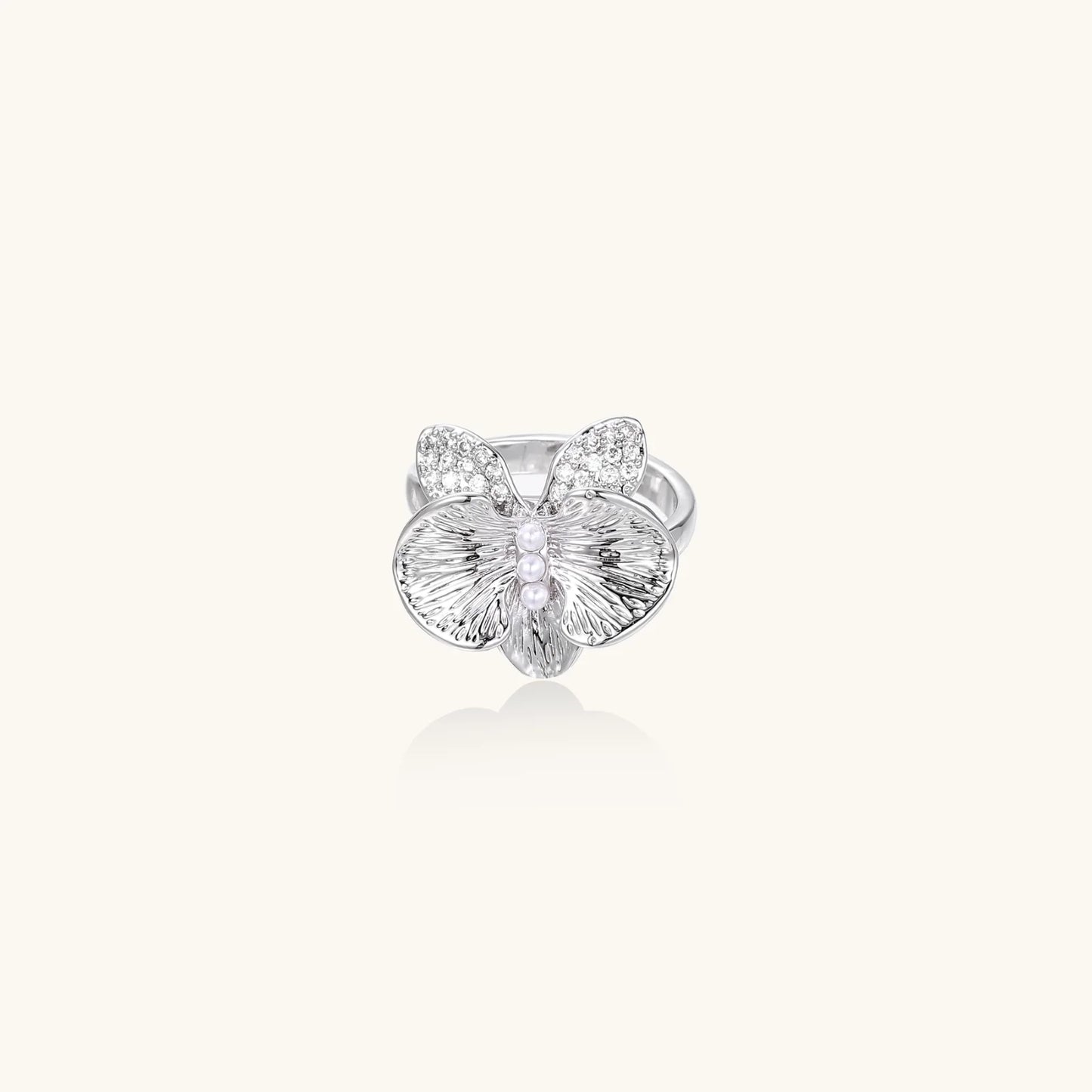 Silver-toned orchid ring with textured petals, pearl center accents, and sparkling zirconia stones on white background.