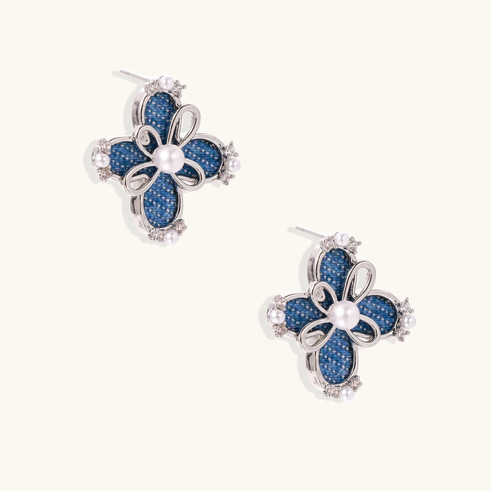 Blue denim fabric flower studs with white gold plated petals, pearl center, and zirconia accents on white background