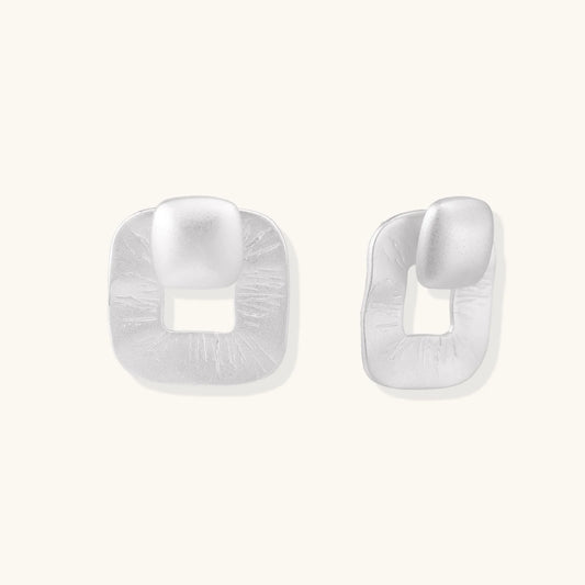 Pair of geometric sterling silver earrings with frosted square frames and glossy rounded studs on white background