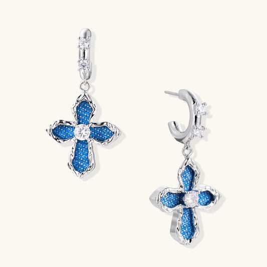 Silver hoops with denim-inlaid cross charms and clear crystals on beige background