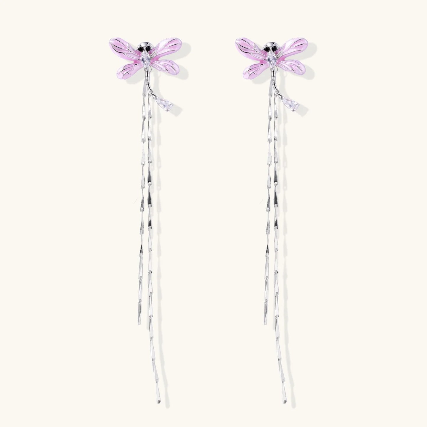 Long drop earrings with translucent lavender enamel dragonfly wings and white gold plated segmented bodies on white background