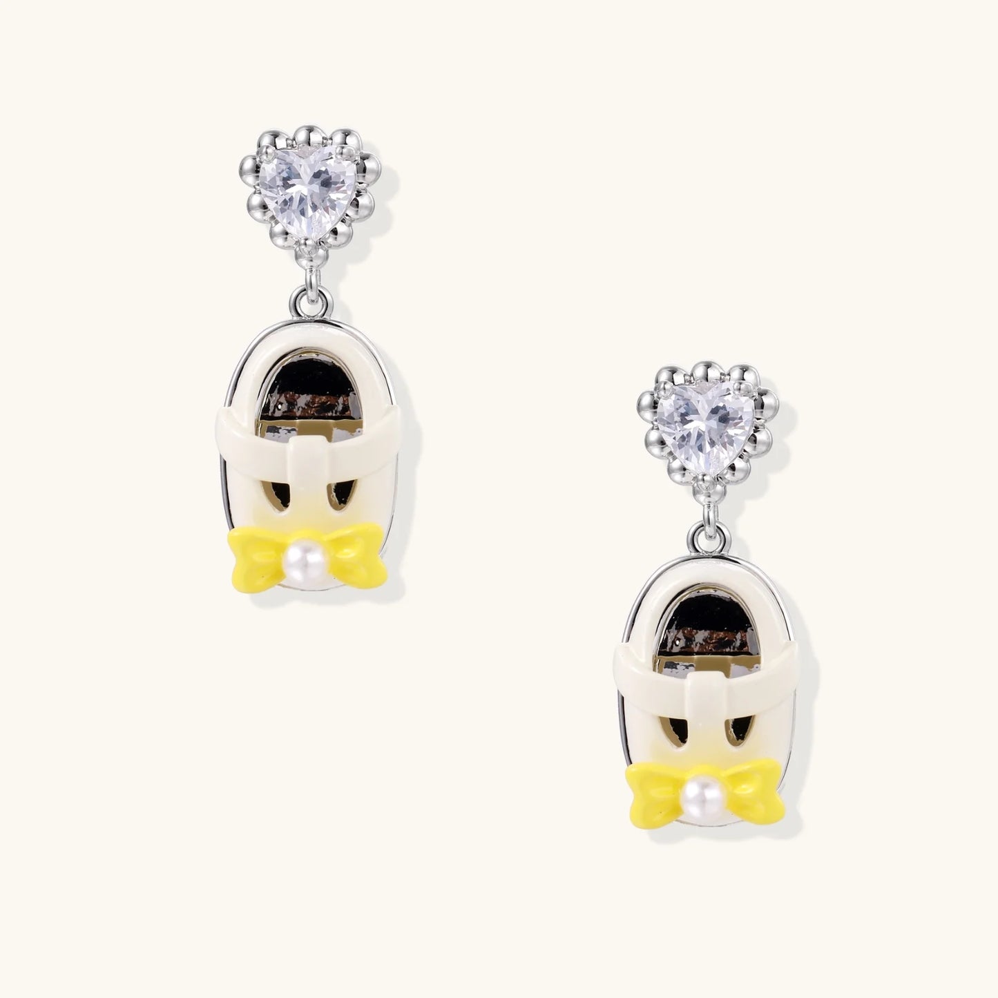 Drop earrings featuring miniature translucent handbag charms with heart crystal studs, silver bow accents, and pearls