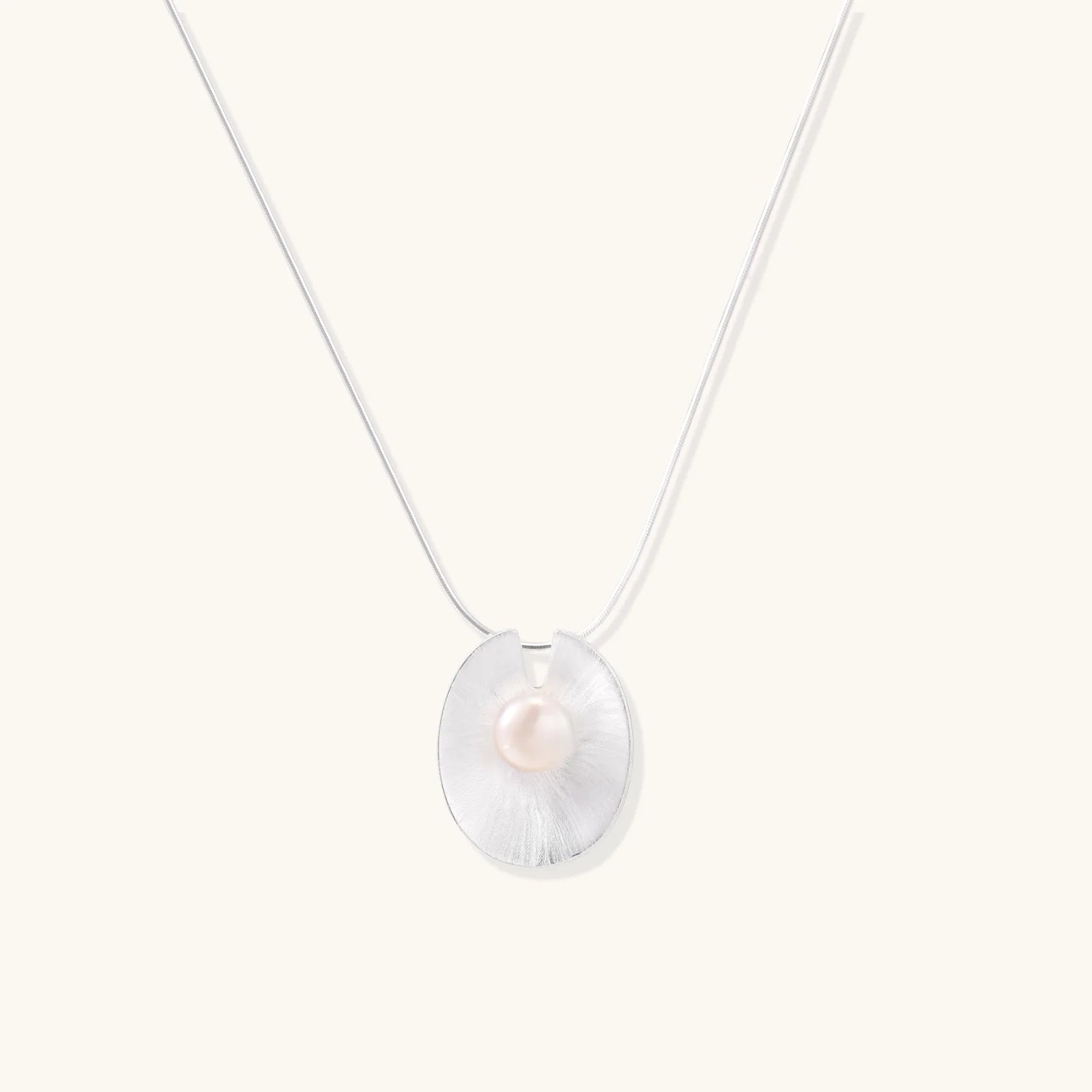 Sterling silver disc necklace with textured finish and centered freshwater pearl on delicate chain