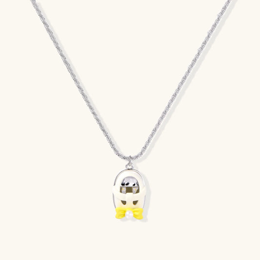 Chrome egg-shaped pendant with kawaii face, yellow bow, and pearl detail on silver chain against white background