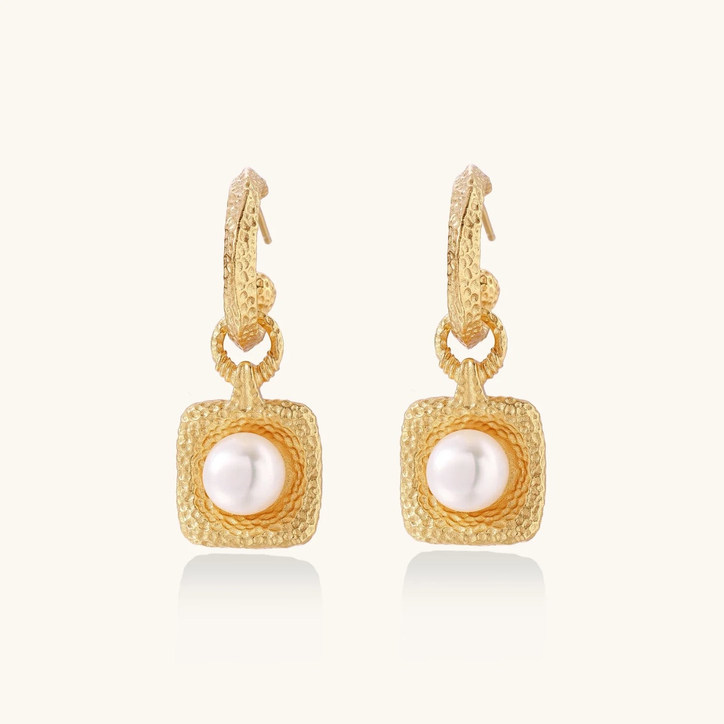 Pair of gold vermeil hoop earrings with textured square frames holding freshwater pearls on cream background