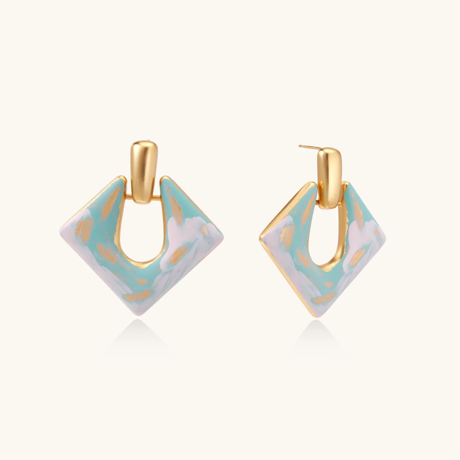Geometric square enamel earrings with marbled turquoise and lavender pattern, gold U-shaped connector on cream background.
